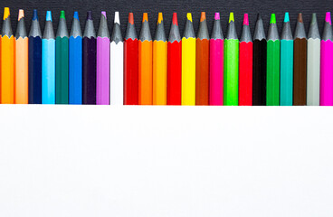 Close-up of colored pencils on a black and white background. Top view with copy space