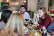 © MandriaPix - stunned expression of young people at restaurant, group of friends eating and drinking red wine in outbreak time of Corona Virus, social gathering and facemasks