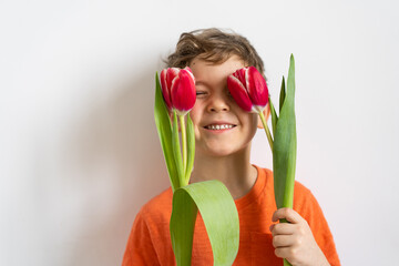 Wall Mural - Cheerful happy child with tulips flower bouquet. Smiling little boy on white background.