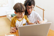 Boy learning laptop with mother