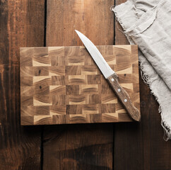 Wall Mural - metal kitchen knife and wooden cutting board on a table made of brown wooden boards