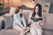 © deagreez - Photo of optimistic brunette red hairdo mom daughter read book on sofa wear sweater pants at home