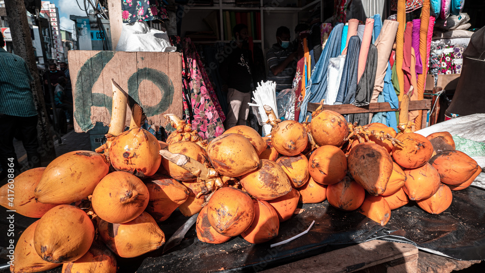 Pomarańczowe owoce kokosowe na stoisku na bazarze. - obrazy, fototapety, plakaty 