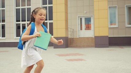 little girl kid with backpack and a fun textbook runs in hurrying to school. education concept. litt
