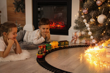 Poster - Children playing with colorful train toy in room decorated for Christmas