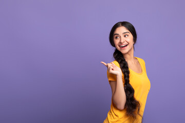 Excited indian woman pointing aside at copy space