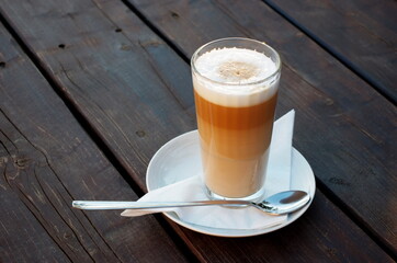 Caffe latte Macchiato, a glass of coffee with frothed milk on a wooden background. Its coffee time.