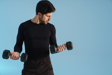 Wall Mural - Handsome athletic sportsman working out with dumbbells