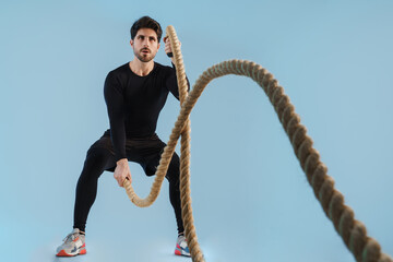 Wall Mural - Handsome athletic sportsman working out with battle ropes