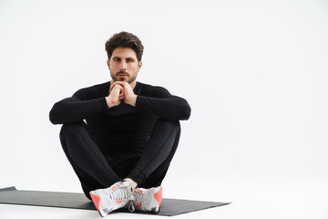 Wall Mural - Young athletic sportsman sitting on mat during workout