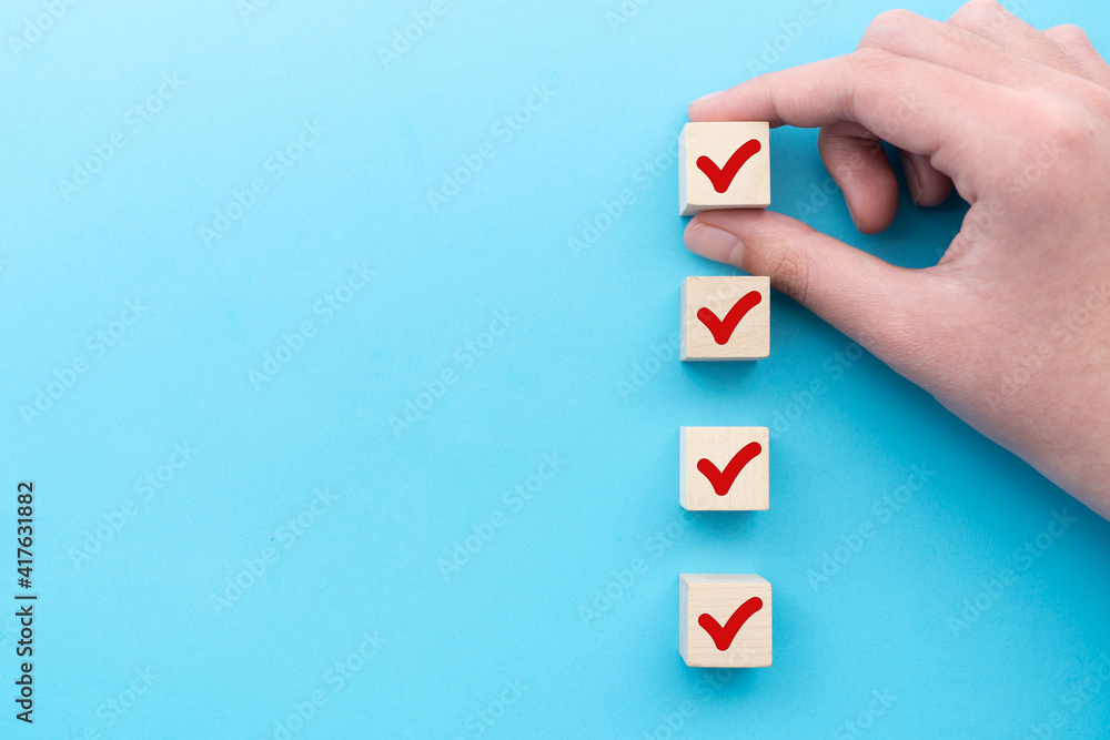 Hand put down the red tick marking wooden cube for checklist or to do list - obrazy, fototapety, plakaty 