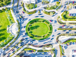 Wall Mural - A roundabout is a type of circular intersection. Top aerial view of a traffic roundabout on a main road in an urban area with cars. Green Lawn and palm trees. Clearwater Beach, Florida US