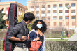© Ladanifer - Latin friends wearing protective face mask walking around the university campus with a guitar case. New normal in the street.