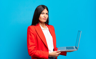 young hispanic woman feeling sad, upset or angry and looking to the side with a negative attitude, frowning in disagreement. laptop concept