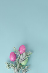 Wall Mural - easter holiday concept. composition of pink and green Easter eggs and delicate fluffy twigs on a blue background. vertical frame, copy space