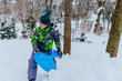 © Iryna - Rosy cheeks school boy in green hat and warm jacket playing outdoor in winter snowy park. Happy healthy childhood in open air.