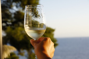 Glass of white wine, tanned skin and a perfect sea view. Skopelos island, Greece.