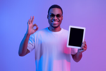 Wall Mural - Happy African Guy In Neon Lighting Holding Digital Tablet With Black Screen