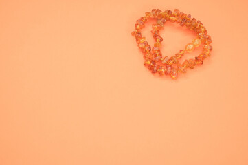 Sticker - Closeup shot of an amber beads necklace on an orange surface