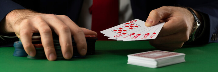 Businessman at green playing table with gambling chips and cards playing poker and blackjack in casino