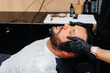 © Andrii - A professional stylist in a modern stylish barbershop shaves and cuts a young man's hair. Beauty salon, hair salon
