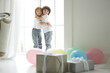 © Friends Stock - Best friends. Two cute latin twin boys, little children in casual wear hugging each other, looking happy, standing in the room with colorful balloons and giftboxes