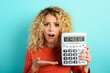 © alphaspirit - Girl is shocked and shows her debt on calculator display. Cyan background