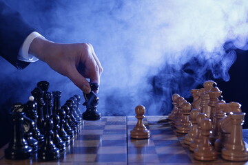 Hand of businessman moving wood chess pieces in a success game competition. Strategy, management or leadership concept