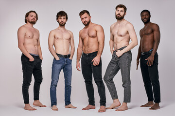 Confident fit guys with naked torso posing together, having serious look. Male models macho, studio shot. portrait