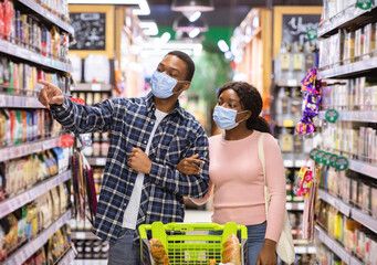 Wall Mural - Millennial black couple in face masks shopping at grocery department of supermarket