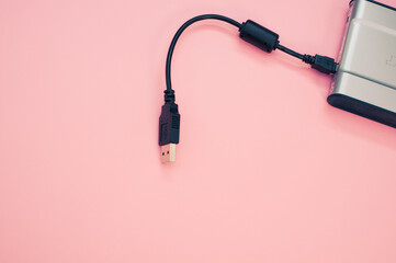 Poster - Closeup shot of a power bank with a cable for charging mobile devices on a pink surface