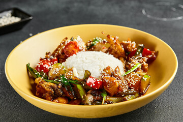 Canvas Print - Sweet and Sour Chicken and Vegetables with Rice. Stir Fry Chicken with Vegetables and Sesame. Yellow plate with wooden chopstick on dark slate table. Chinese, asian, authentic food concept