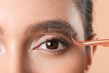 Beautiful young woman applying fake eyelashes, closeup