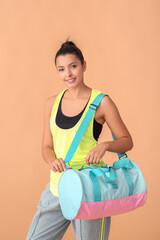 Wall Mural - Young woman with sports bag on color background