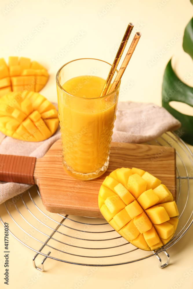 Glass of tasty mango smoothie on color background