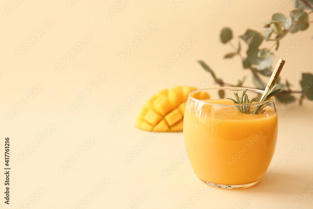 Glass of tasty mango smoothie on color background