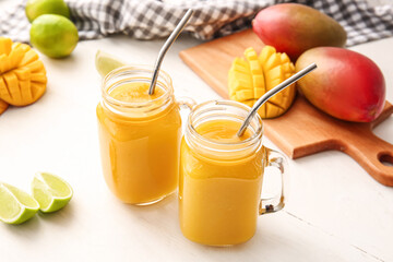 Wall Mural - Mason jars of tasty mango smoothie on light background