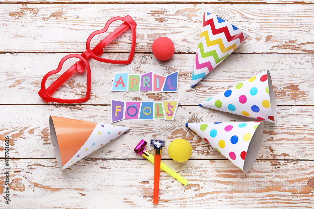 Party decor for April Fools Day on white wooden background