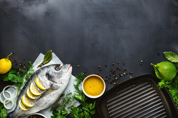Poster - Fresh borabo fish with grill pan and ingredients for cooking on dark background top view. Delicious and healthy food