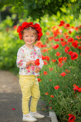 Portrait of a beautiful little girl having fun in field of red poppy flowers in spring.