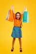 Excited little girl with shopping bags in raised hands