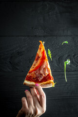 Wall Mural - Top view of hand take homemade pizza with arugula isolated on black background. vertical image. banner, menu recipe place for text