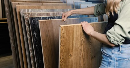 Wall Mural - woman choosing wood texture laminate floor in flooring store