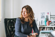 © Galina Zhigalova - Charming smiling adult woman middle aged woman with curly hair architect designer in the bright modern office
