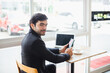© eakgrungenerd - Young man bearded wear black suit in cafe seat side glass window holding smartphone with laptop and coffee cup on table. businessman working relax time in restaurant.