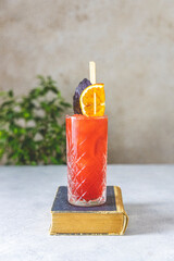 Wall Mural - Old-fashioned cocktail with  slice blood oranges and red basil on the light gray table surface. Selective focus. Shallow depth of field