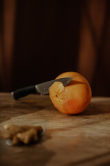 Poster - Vertical closeup shot of a knife on an orange on a cutting board