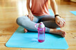 © Syda Productions - fitness, sports accessories and healthy lifestyle concept - woman with water bottle resting on yoga mat in gym or studio