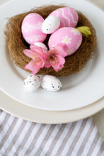 Food Decoration. Easter Holiday. Festive Dinner. Pink White Painted Egg Set With Minimal Modern Pattern Spring Flowers In Nest Served In Plate On Striped Tablecloth.