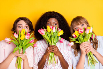 Poster - Portrait of three pretty persons hands hold fresh flowers covering mouth isolated on yellow color background